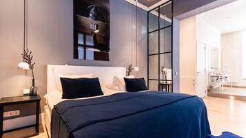 A modern bedroom with a large bed, a nightstand, a wall-mounted clock, and a sliding door leading to a bathroom.