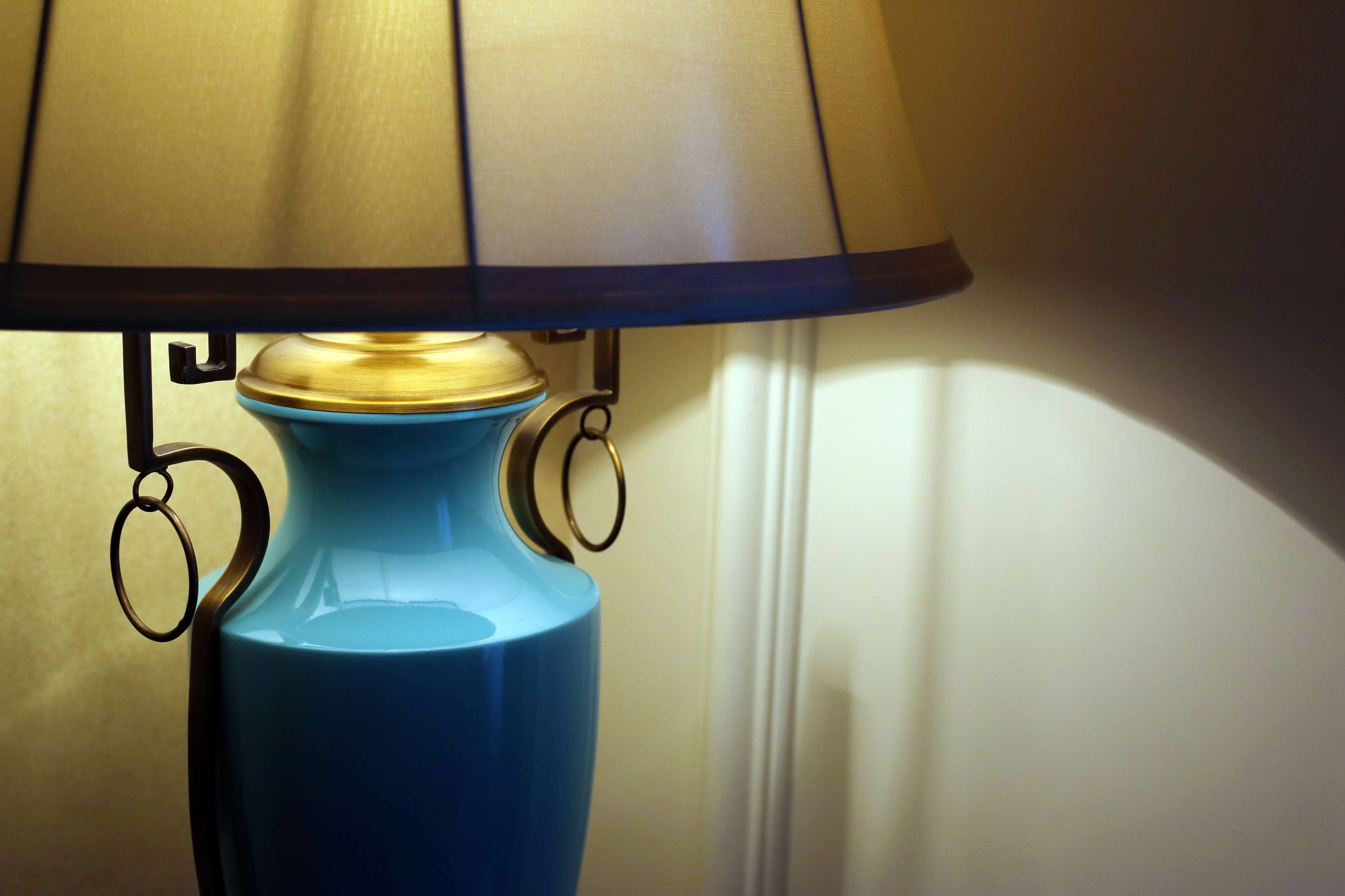 A blue table lamp with a gold base and a beige lampshade.