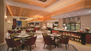 Ein modernes Restaurant mit hohen Decken, verschiedenen Essbereichen und einer zentralen Bar.