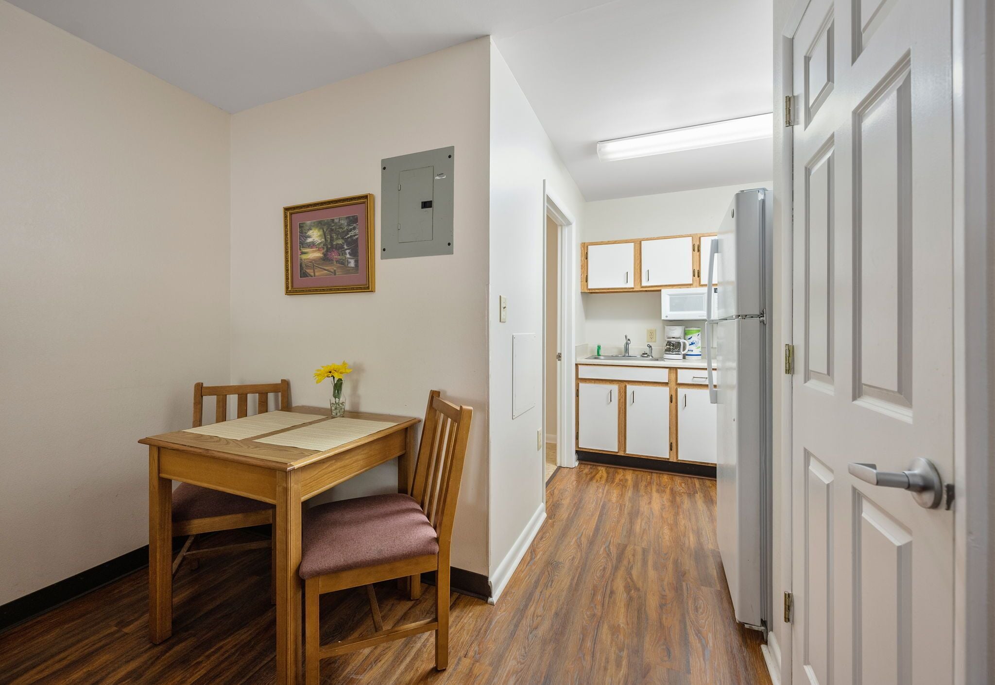 A compact kitchen with white cabinets and a refrigerator.
