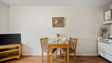 A compact kitchen with a dining table, chairs, a TV, and a stove.