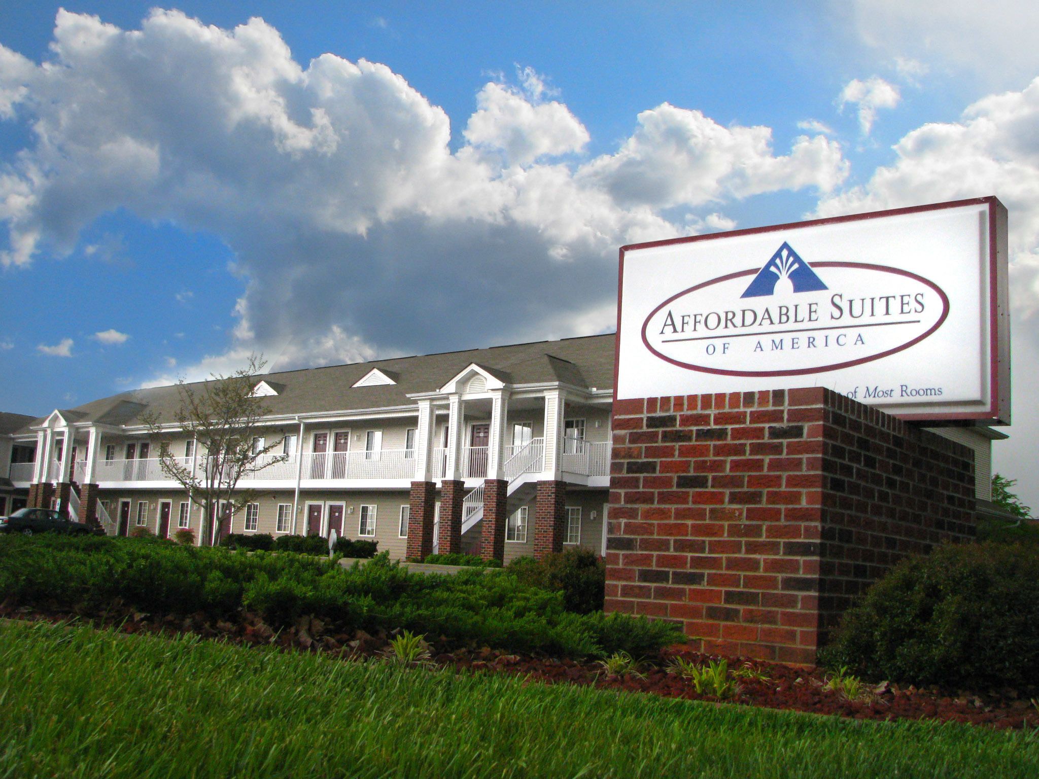 A hotel with a sign reading "Affordable Suites of America" and a brick building facade.