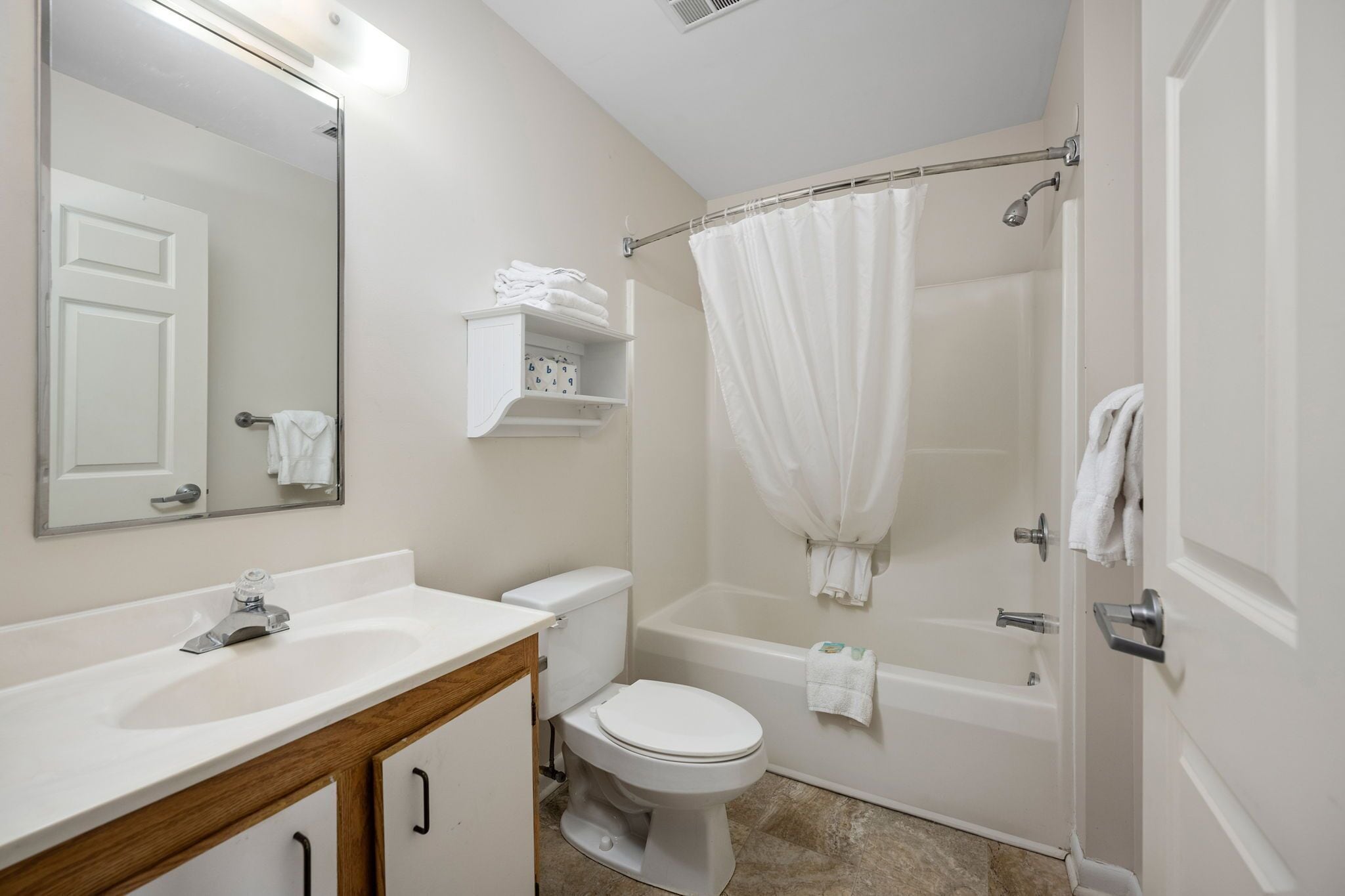 A bathroom with a white sink, toilet, and bathtub. There is a mirror above the sink and a towel rack above the bathtub.