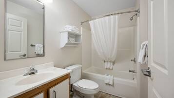 A bathroom with a white sink, toilet, and bathtub. There is a mirror above the sink and a towel rack above the bathtub.