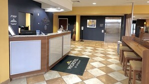 A hotel lobby with a reception desk, a vending machine, and a seating area with a check-in counter.