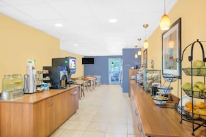 Um café com um balcão comprido, uma máquina de café e diversos alimentos expostos.