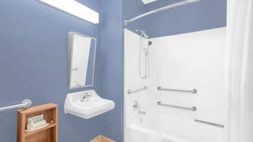A bathroom with a white bathtub, a sink, a mirror, and a wooden medicine cabinet.