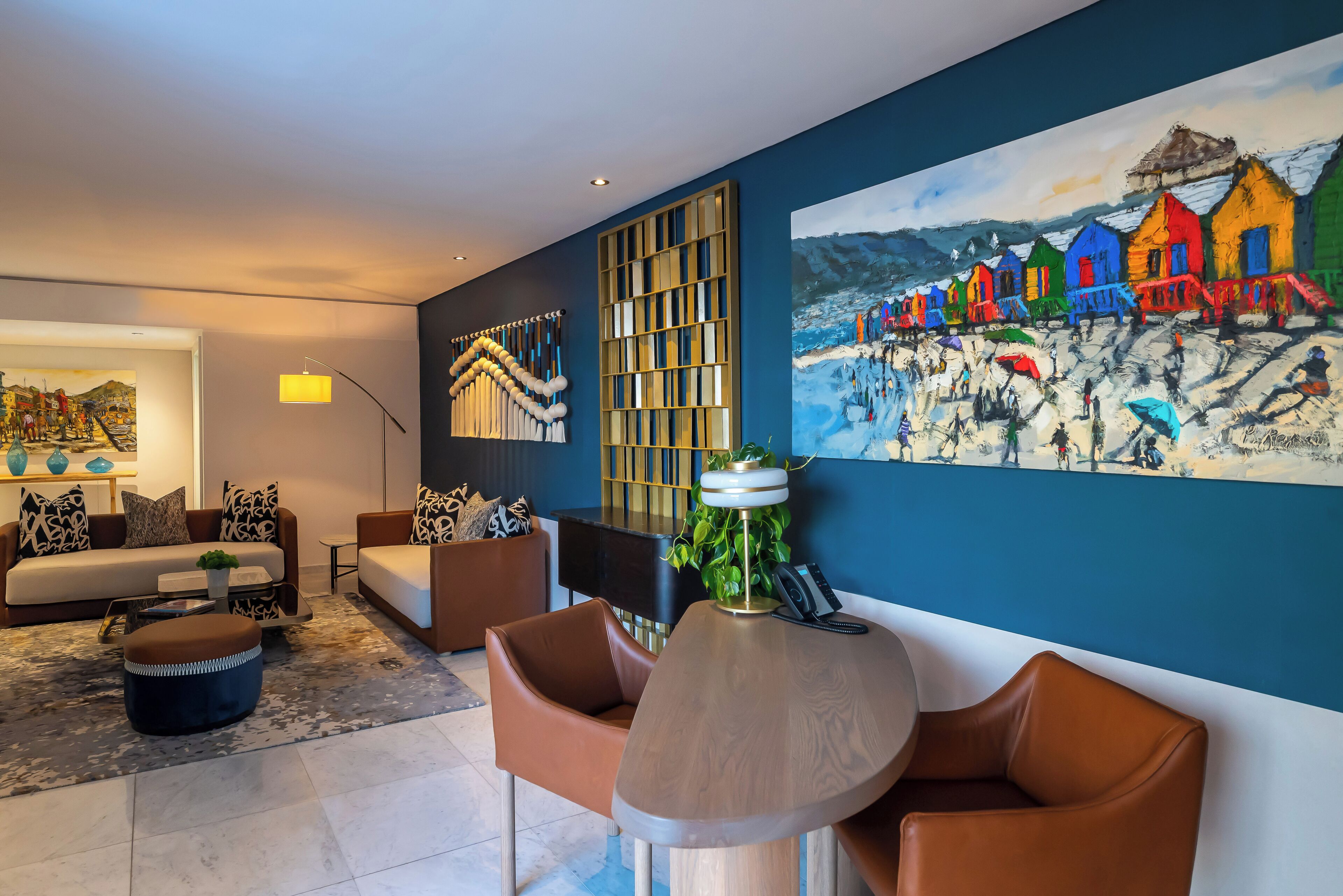 A modern living room with a large painting of colorful houses, a sofa set, and a coffee table.