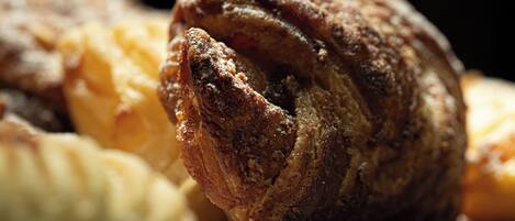 A close-up of a baked pastry with a golden-brown crust, possibly a croissant or similar bread, with a dusting of flour on top.