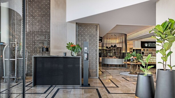 A modern lobby with a geometric ceiling design, a reception desk, and a coffee bar. - Hyatt Regency Cape Town (Cape Town)