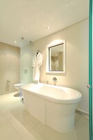 Un baño moderno con una bañera independiente, una cabina de ducha con paredes de vidrio y un espejo grande sobre el lavamanos.