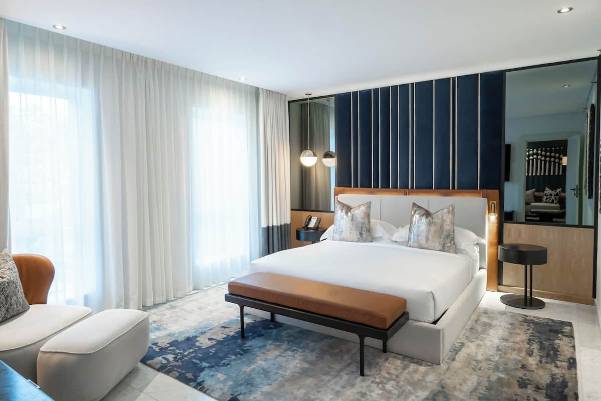 Une chambre d’hôtel moderne avec un grand lit, un banc, un bureau et une vue sur la ville.