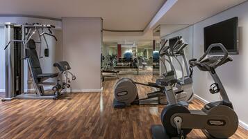 Un gimnasio con equipo de ejercicio, un espejo grande y suelo de madera.