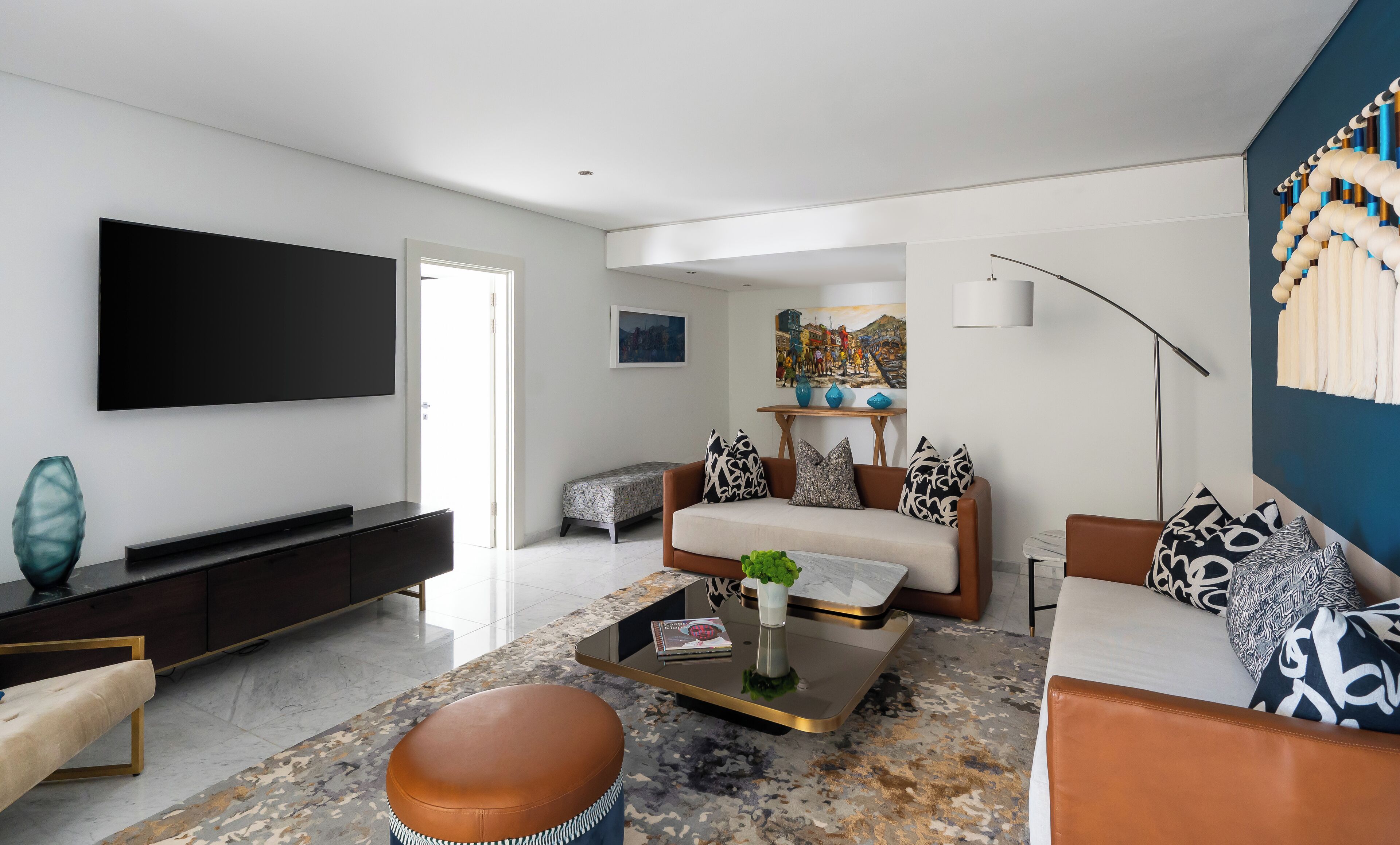 Una sala de estar moderna con un televisor de pantalla plana, un sofá, una mesa de centro y una alfombra estampada.