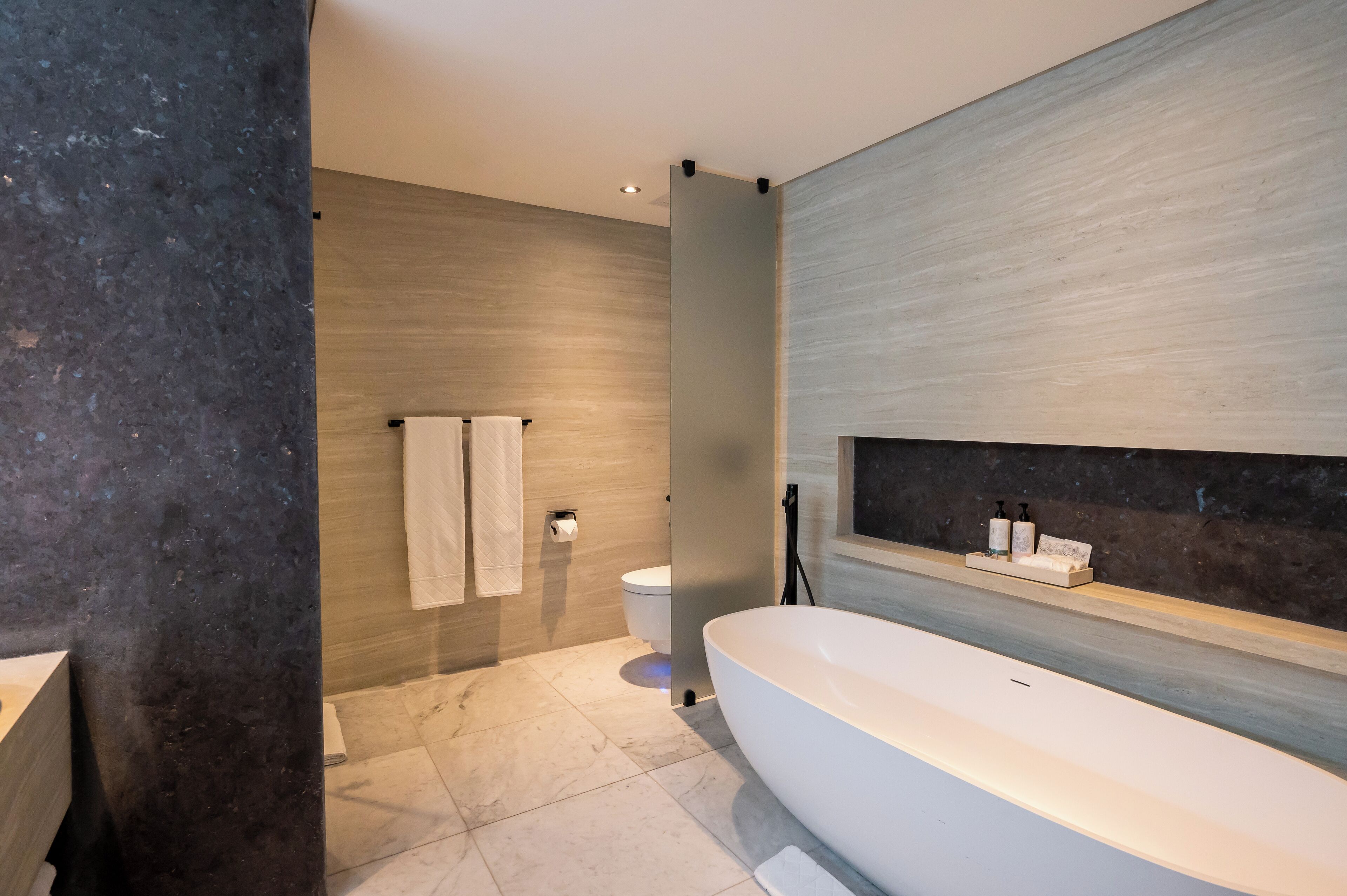 Un baño moderno con una bañera grande, un inodoro y un lavabo.