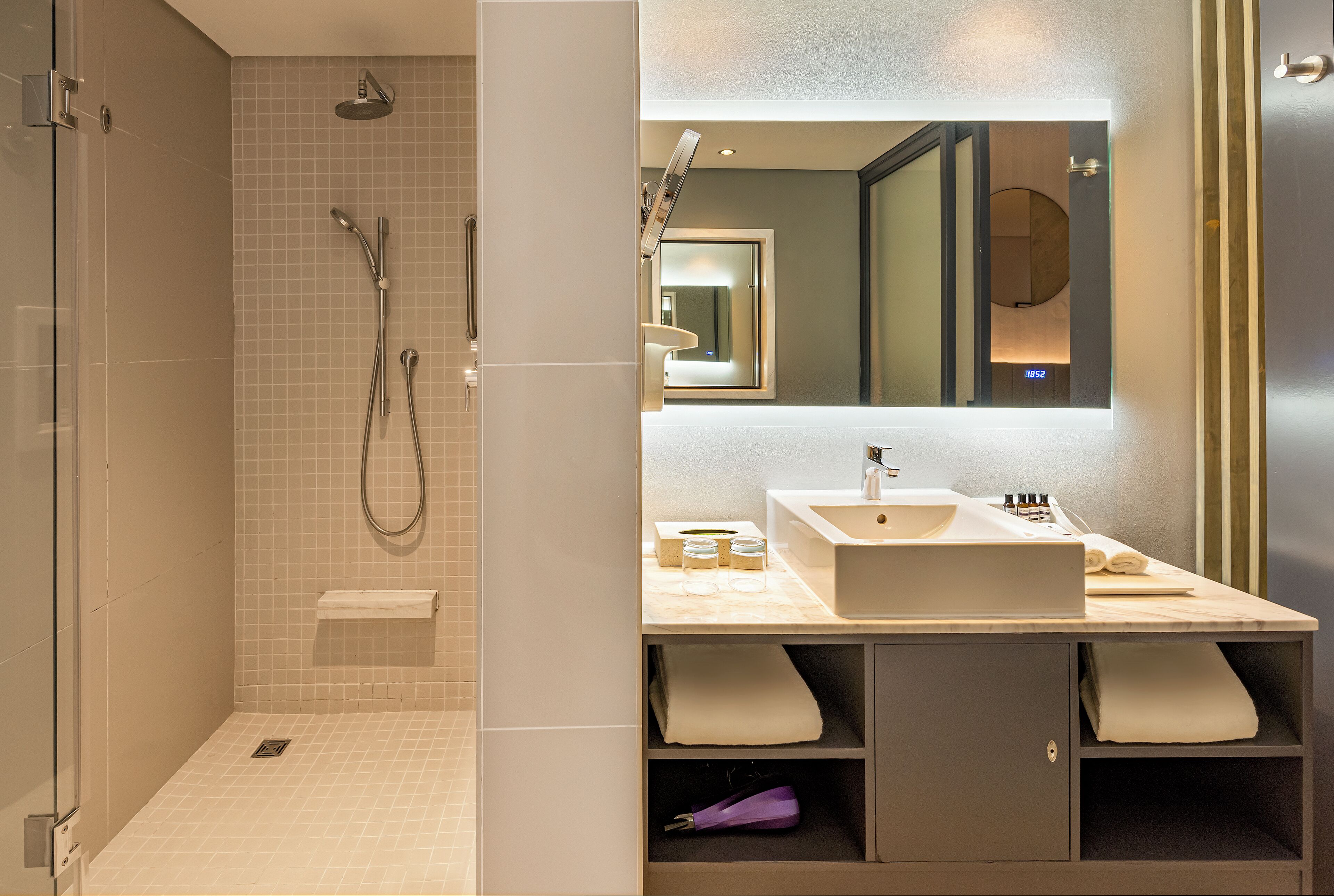 Un baño moderno con ducha, lavamanos y espejo.