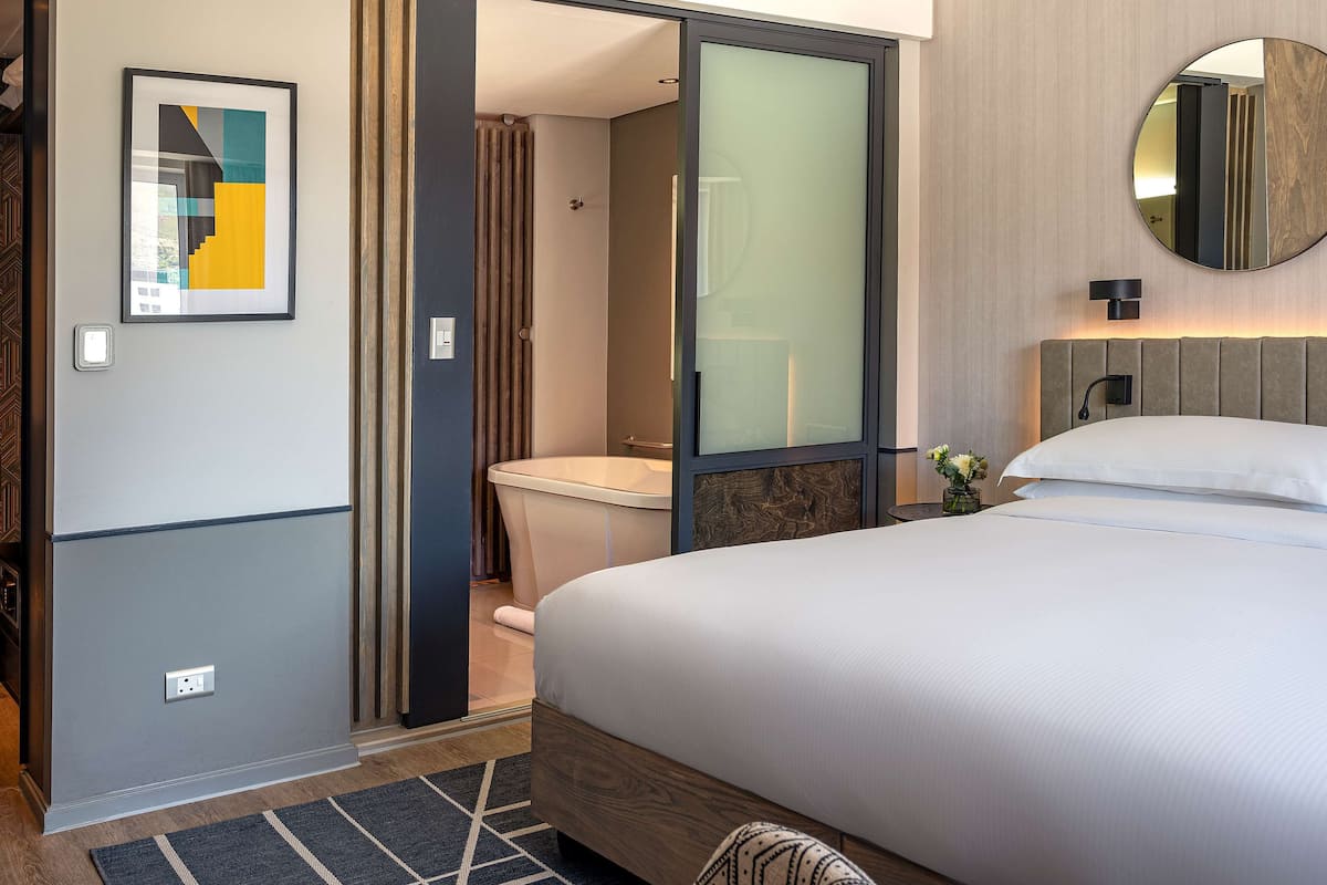 Une chambre d’hôtel moderne équipée d’un lit, d’une salle de bain et d’un grand miroir.