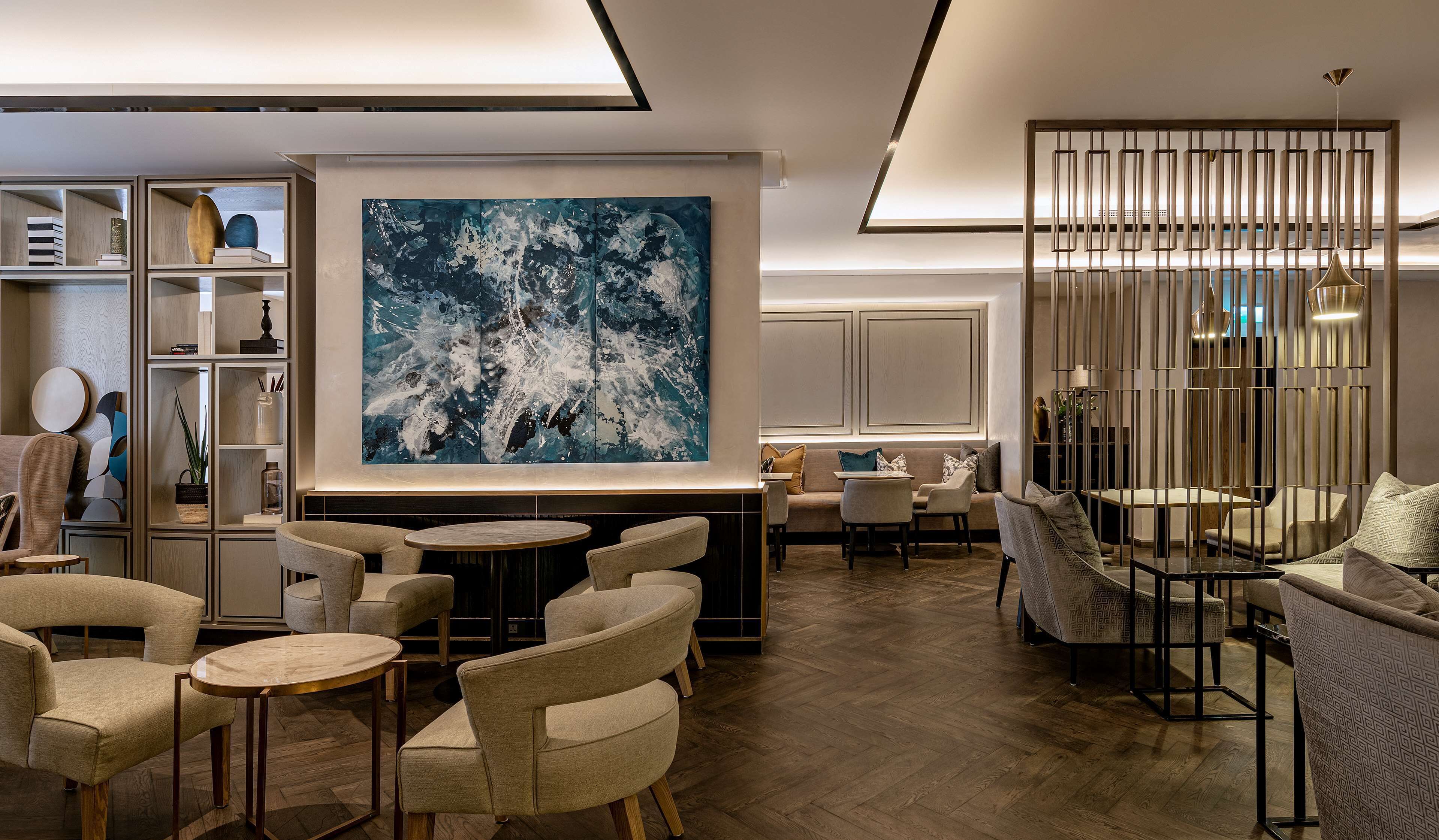 A modern lounge area with a large abstract painting, comfortable seating, and a decorative partition.