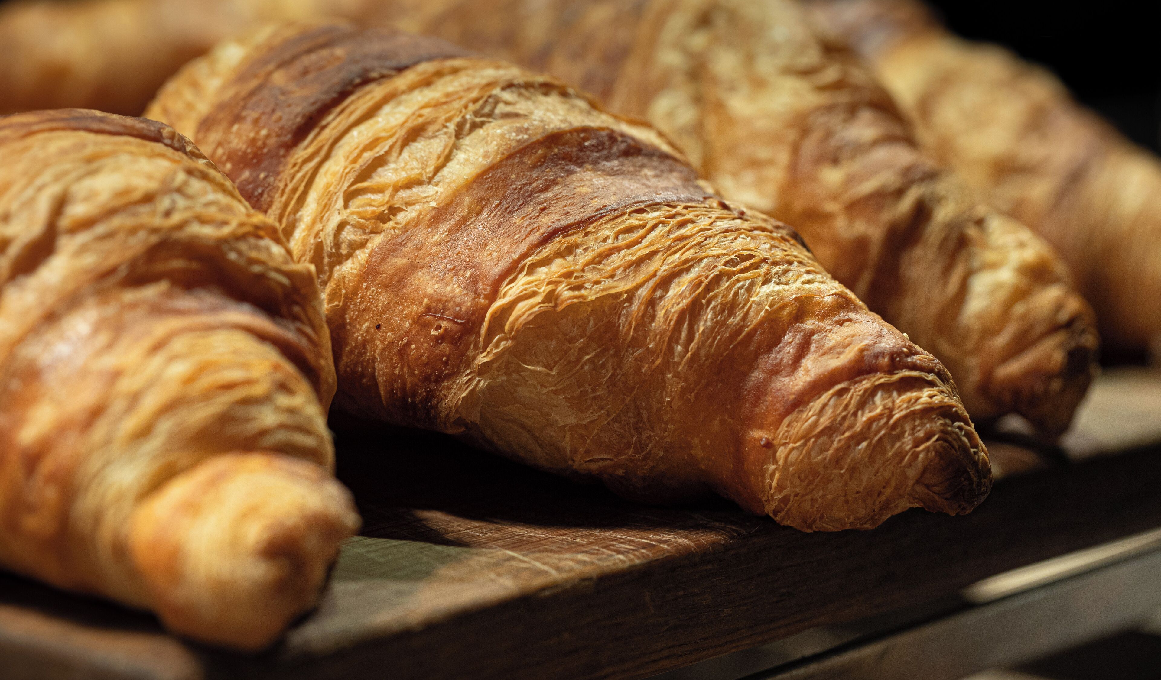 A close-up of several croissants on a wooden surface.