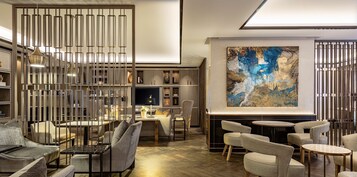 A modern interior with a dining area, sofas, and a large abstract painting.