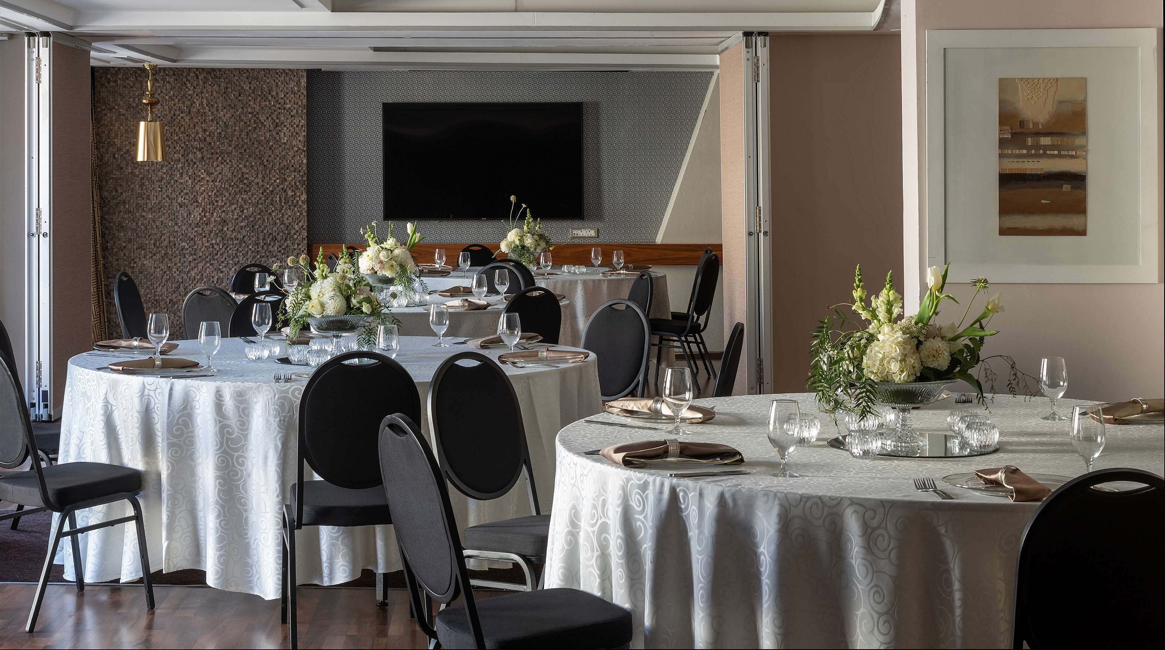 Un espace repas avec des tables rondes, des chaises et des centres de table floraux.