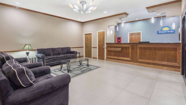 A reception area with a Days Inn sign, a reception desk, a sofa, and a lamp. - Days Inn by Wyndham Baytown East (Baytown)
