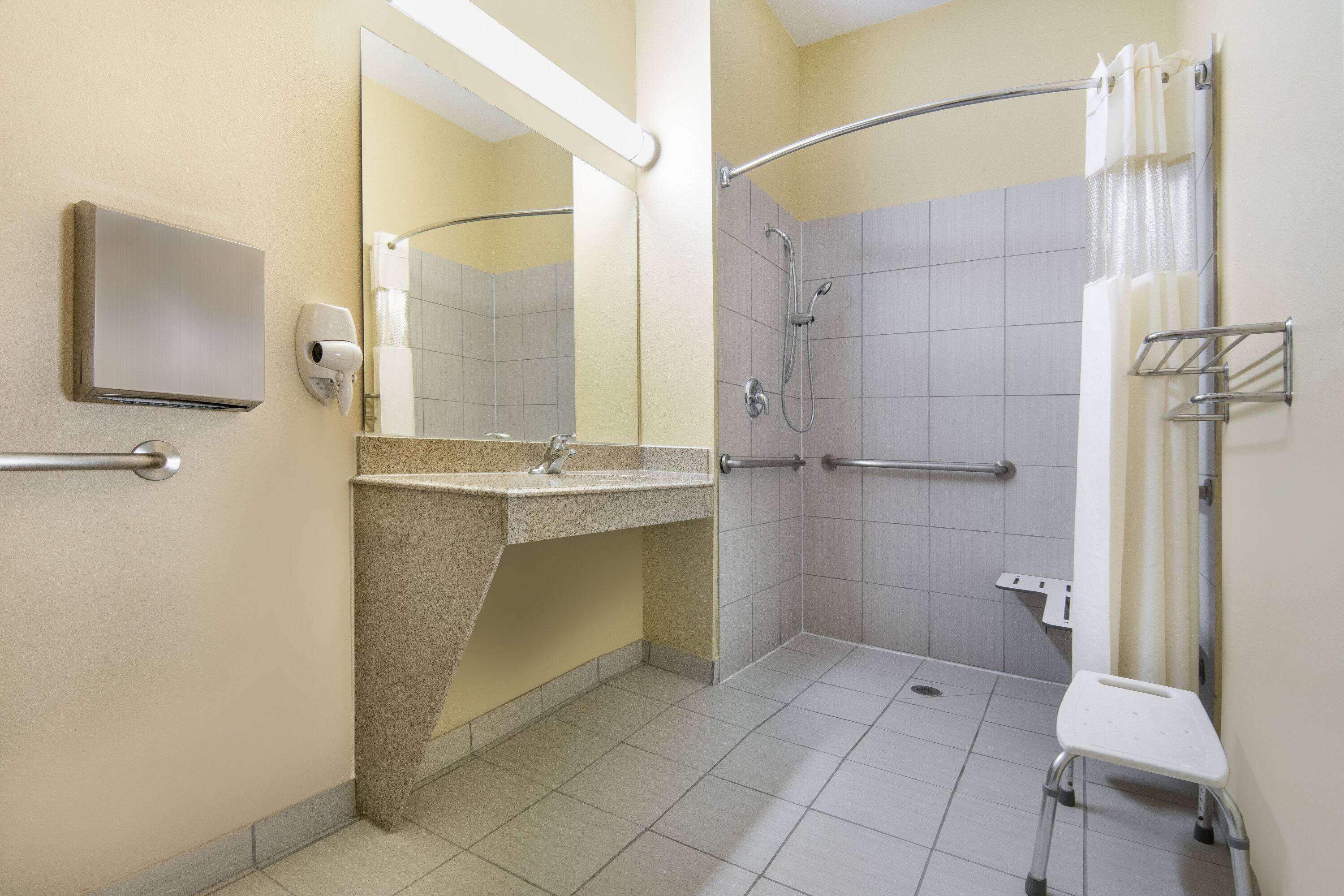 A handicap-accessible bathroom with a shower, grab bars, and a hand dryer.