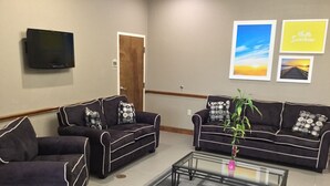 A modern living room with two sofas, a coffee table, and a TV mounted on the wall. - Days Inn by Wyndham Baytown East (Baytown)