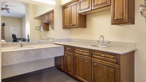 A kitchen with wooden cabinets, granite countertops, and a ceiling fan. - Days Inn by Wyndham Baytown East (Baytown)