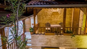 A balcony with a wooden railing, a table, and chairs. There is a potted plant on the balcony. - Zeynep Hanim Konagi - Special Class (Gaziantep)