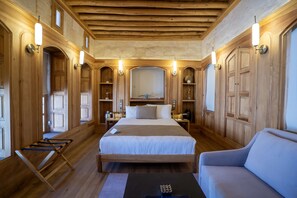A wooden room with a bed, a sofa, and a desk with a lamp.