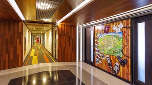 A hallway with wooden paneling, a tiled floor, and a large wall mural. - ibis Styles Chiang Mai (Chiang Mai)