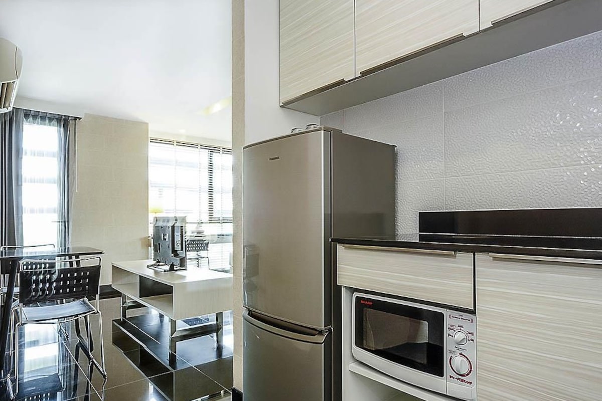 A modern kitchen with a stainless steel refrigerator, a built-in microwave, and a dining area with a table and chairs.