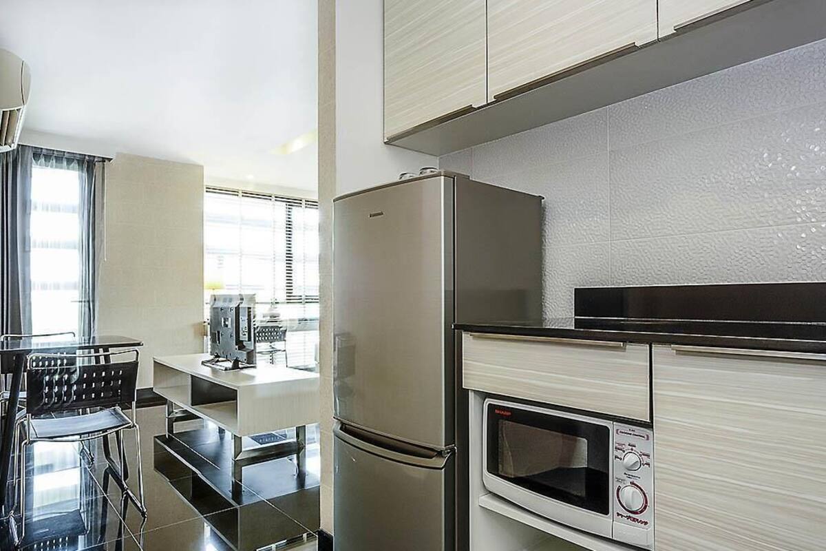 A modern kitchen with a stainless steel refrigerator, a built-in microwave, and a dining area with a table and chairs.