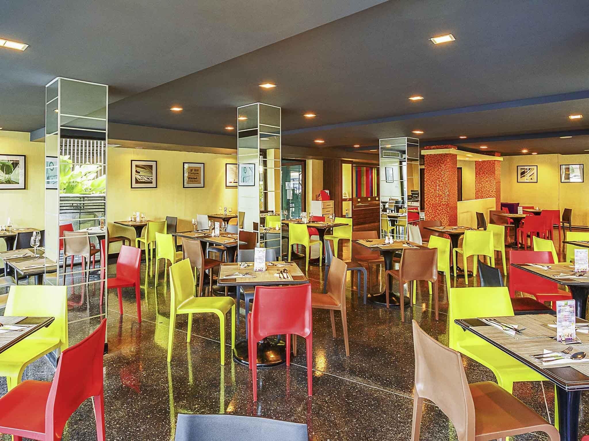 A restaurant with multiple tables and chairs, a polished floor, and framed pictures on the walls.