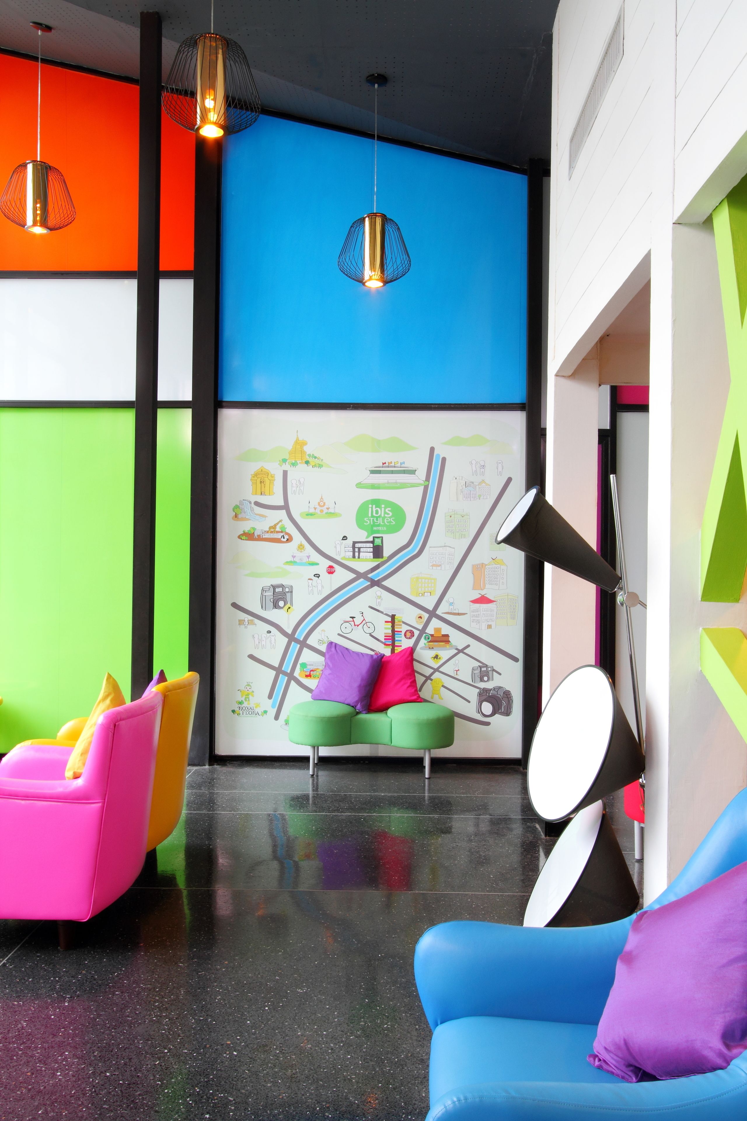 Un vestíbulo moderno con asientos coloridos, un mural de mapa e iluminación colgante.