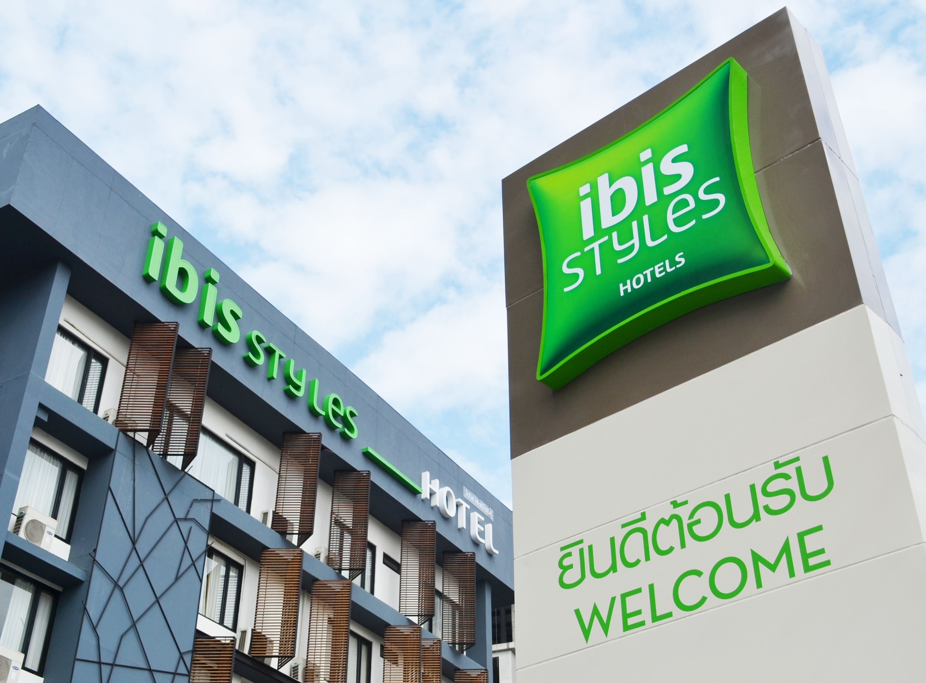 A hotel sign with "ibis styles hotels" and "WELCOME" in green text.