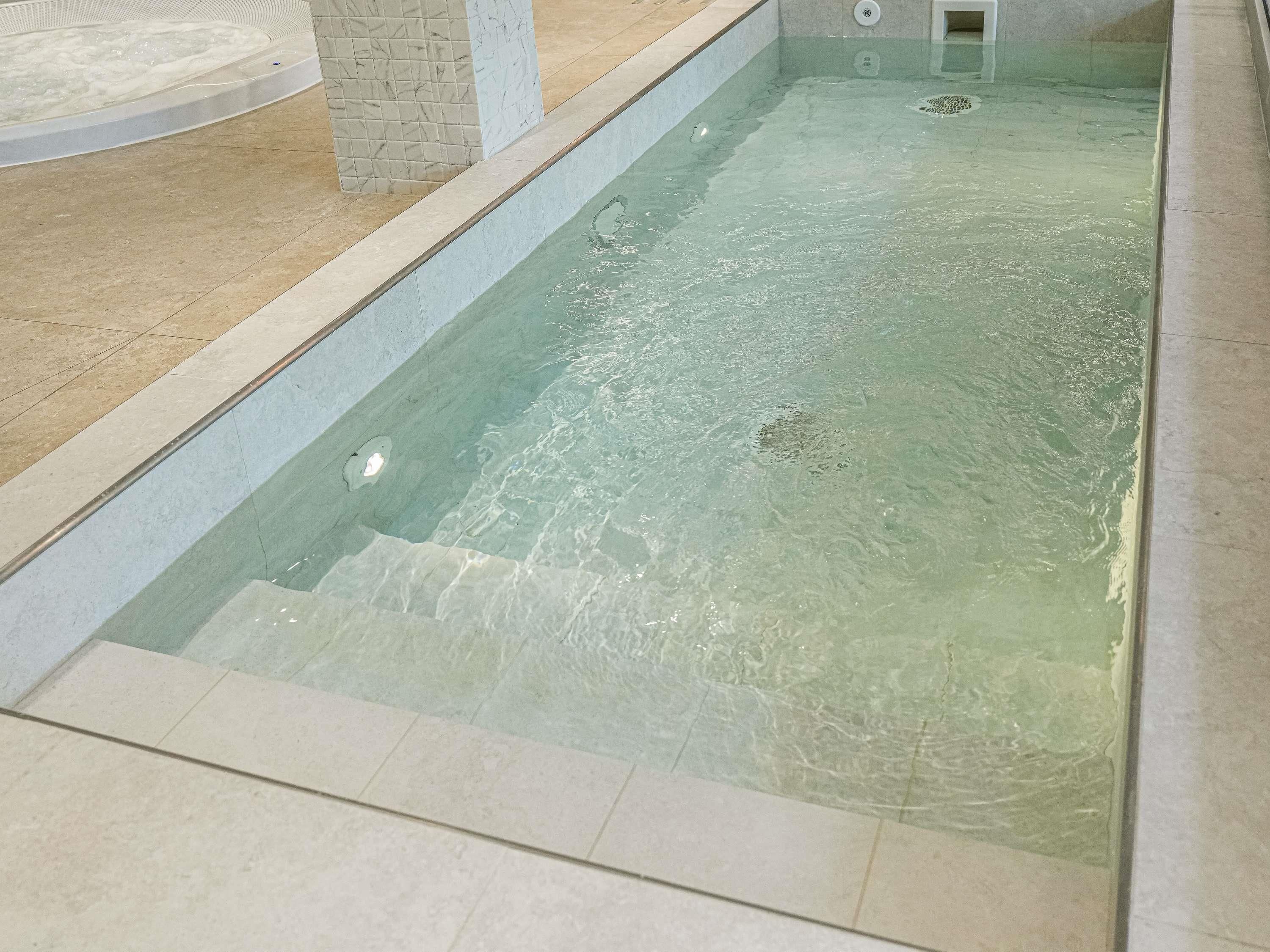 Piscina com água cristalina, bordas e piso revestidos em azulejo.