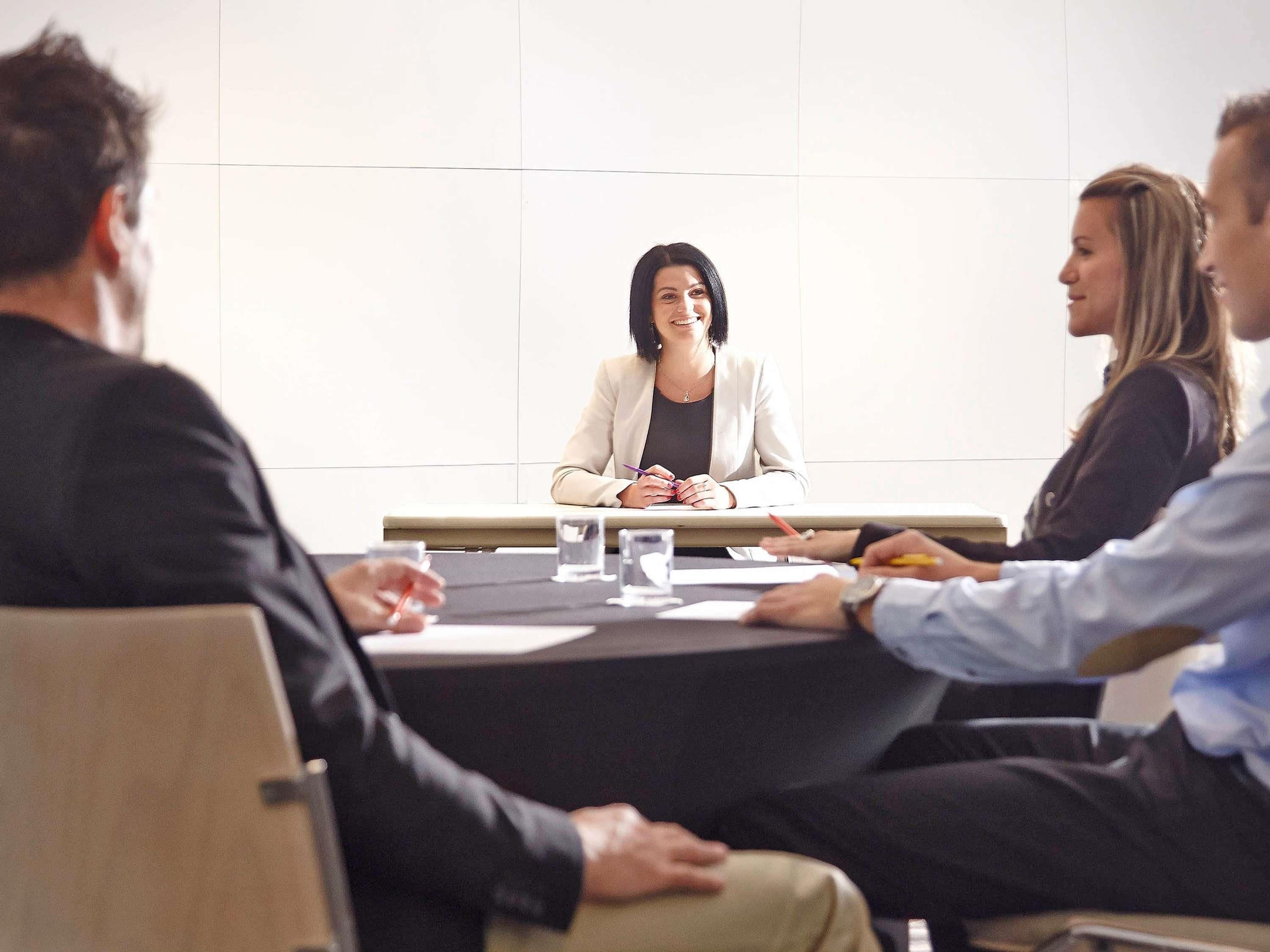 A conference room with a long table, chairs, and a whiteboard.