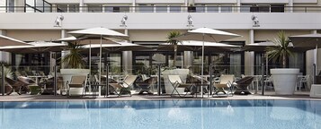 Una piscina al aire libre, sillones reclinables de piscina