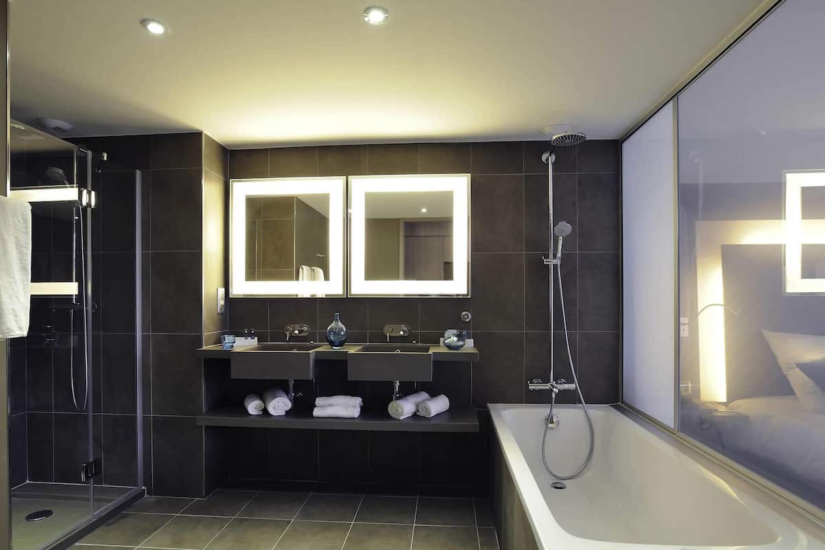 Ein modernes Badezimmer mit einer einteiligen Duschkabine, einer großzügigen Badewanne und zwei Waschbecken mit Schminkspiegeln.