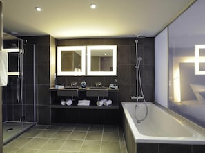 A modern bathroom with a glass-enclosed shower, a large bathtub, and dual sinks with vanity mirrors. - Novotel Avignon Centre (Avignon)