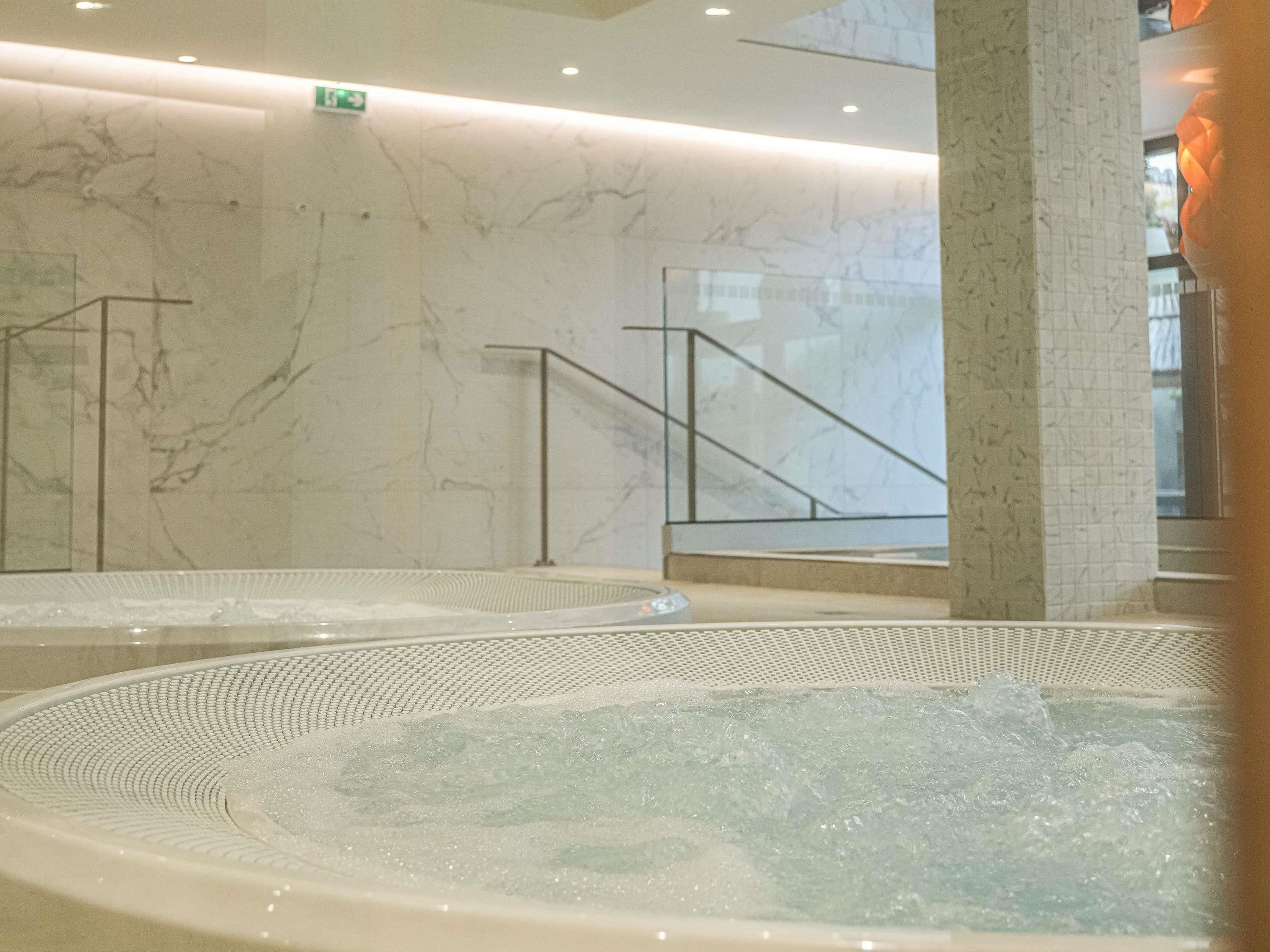 A spa area with marble walls, a hot tub, and a staircase.
