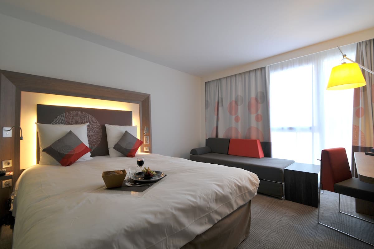Ett hotellrum med en stor säng, ett skrivbord och en soffa.