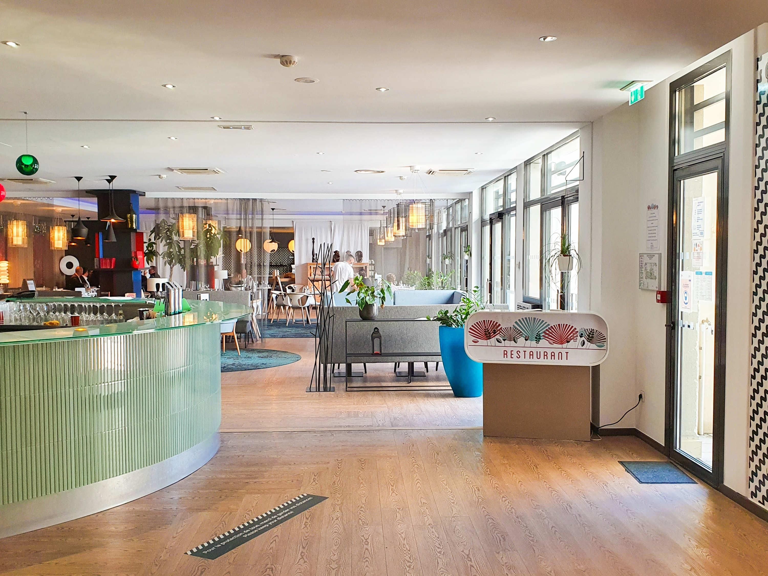 Interior moderno de restaurante con barra, asientos y mostrador de recepción.