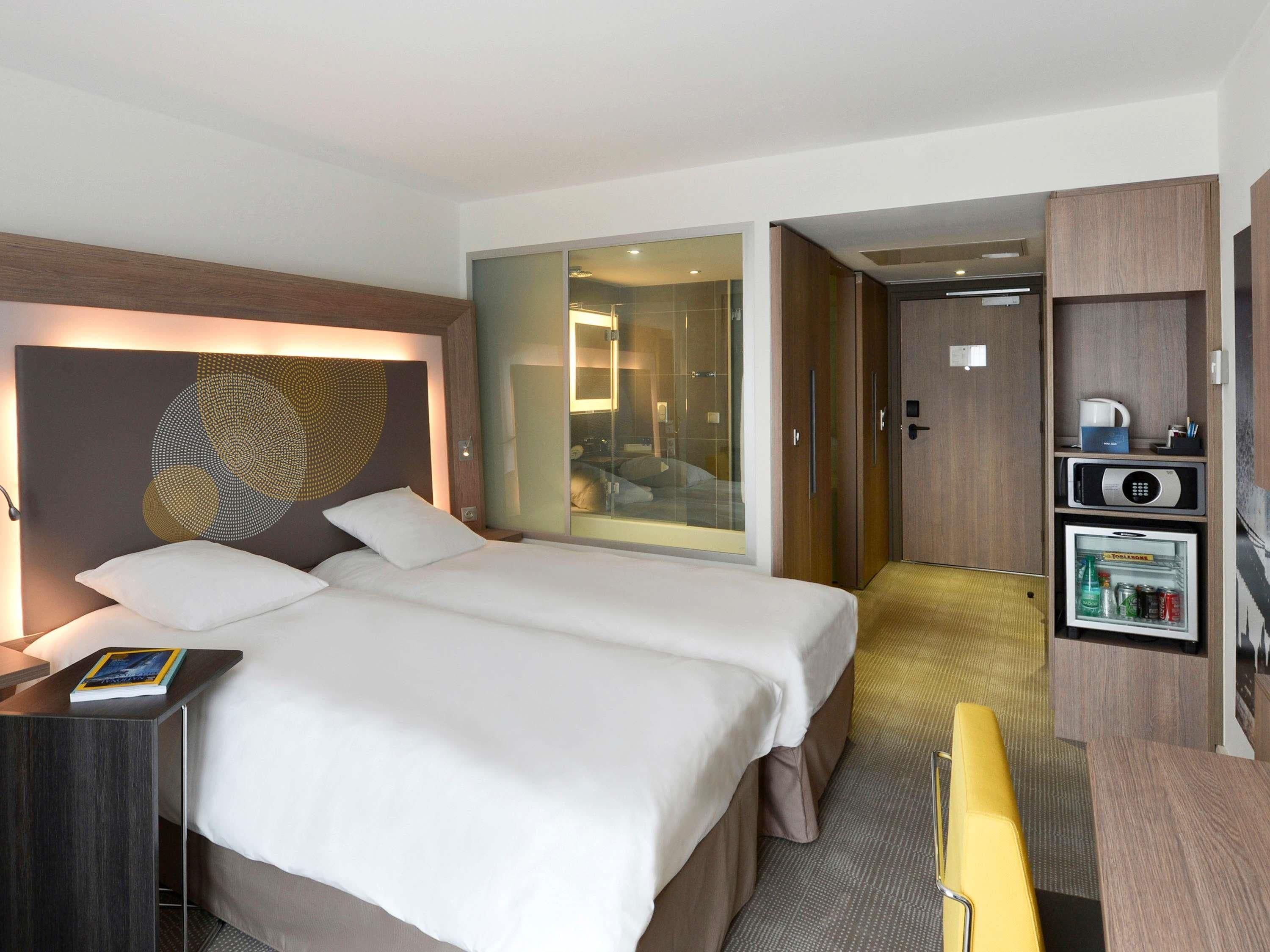 Een hotelkamer met een bed, een bureau, een minibar en uitzicht op een badkamer.