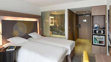 Een hotelkamer met een bed, een bureau, een minibar en uitzicht op een badkamer.