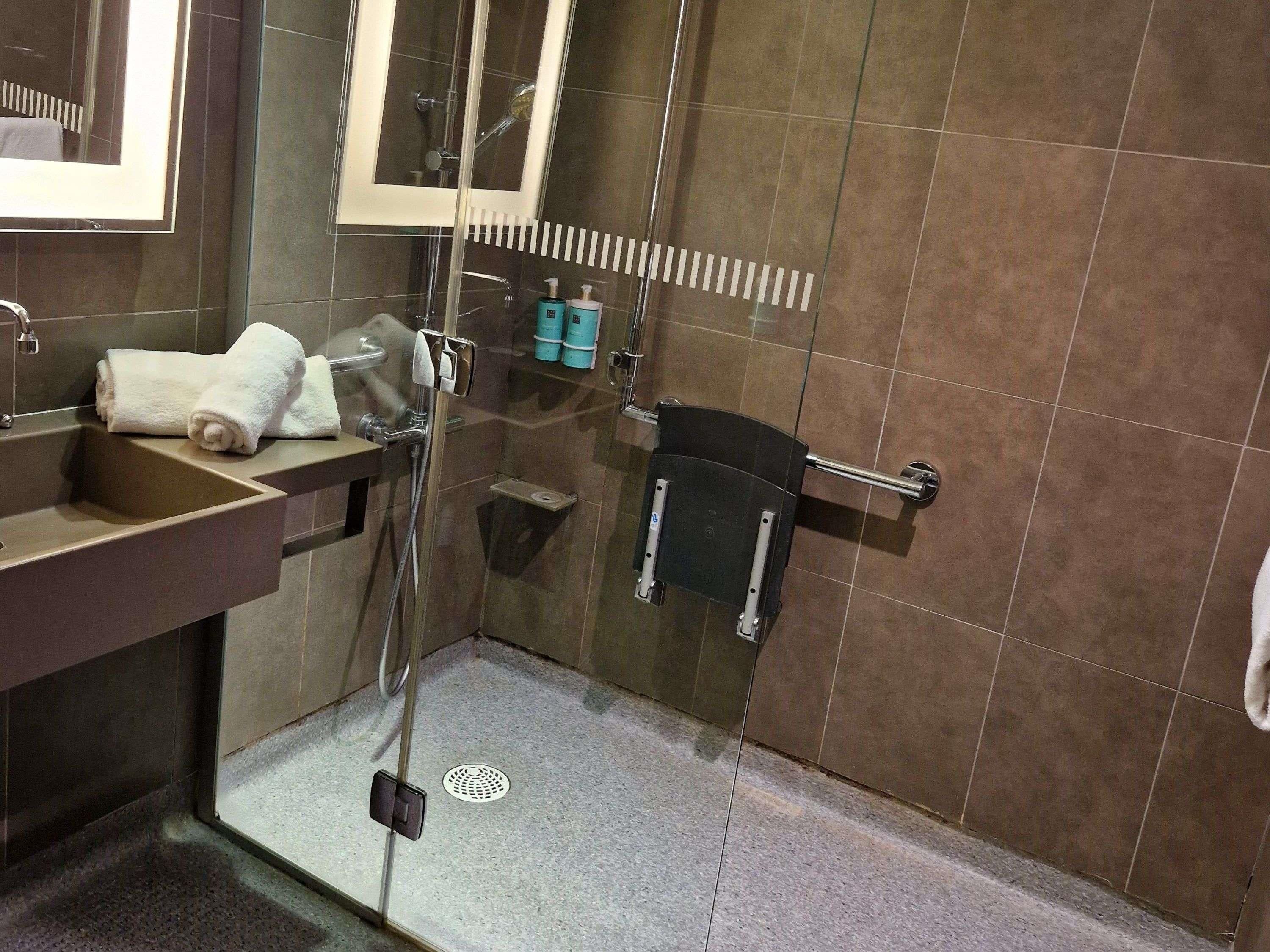 Un baño con lavabo, espejo, toallero, ducha y artículos de aseo.