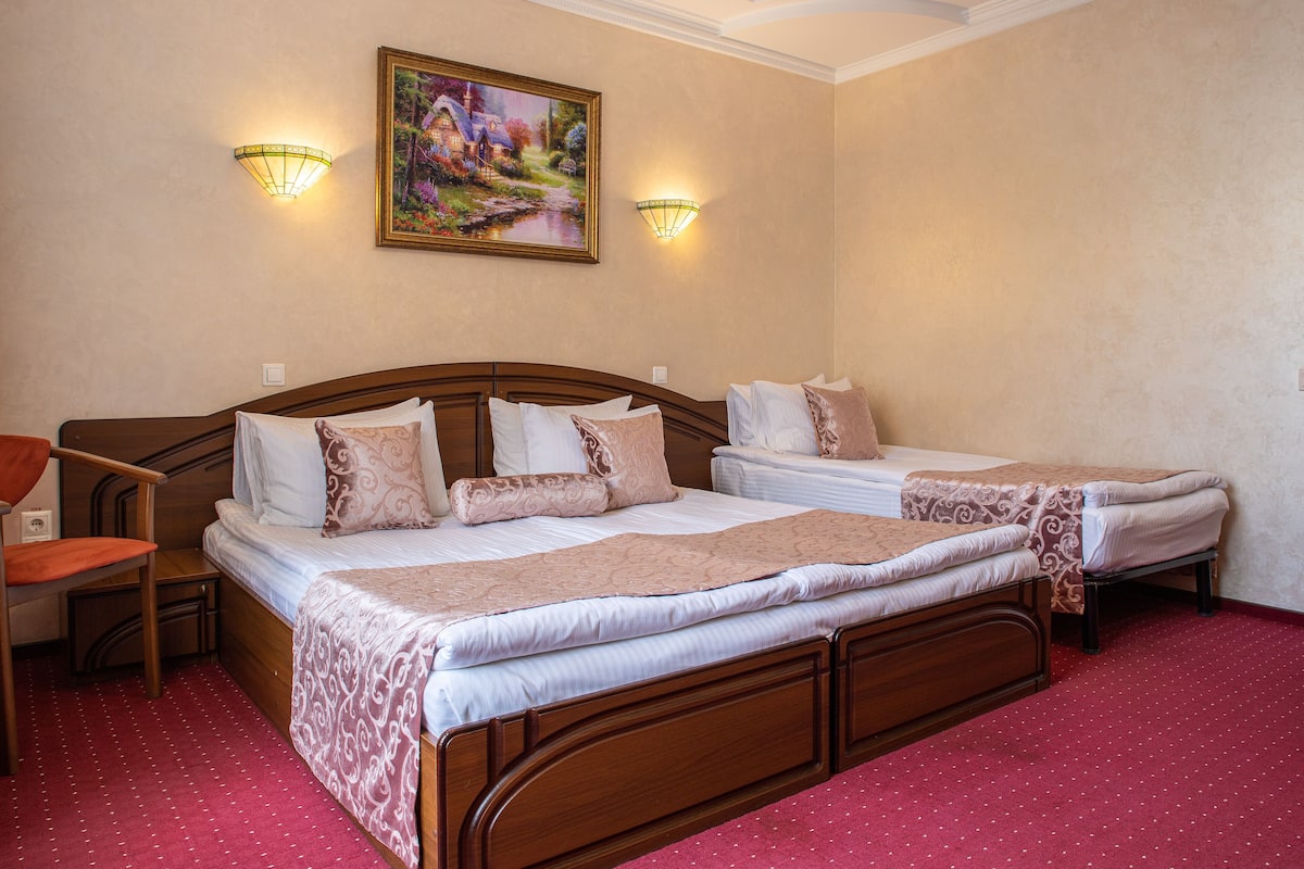A hotel room with two beds, a wooden headboard, a red carpet, and two wall-mounted lamps.