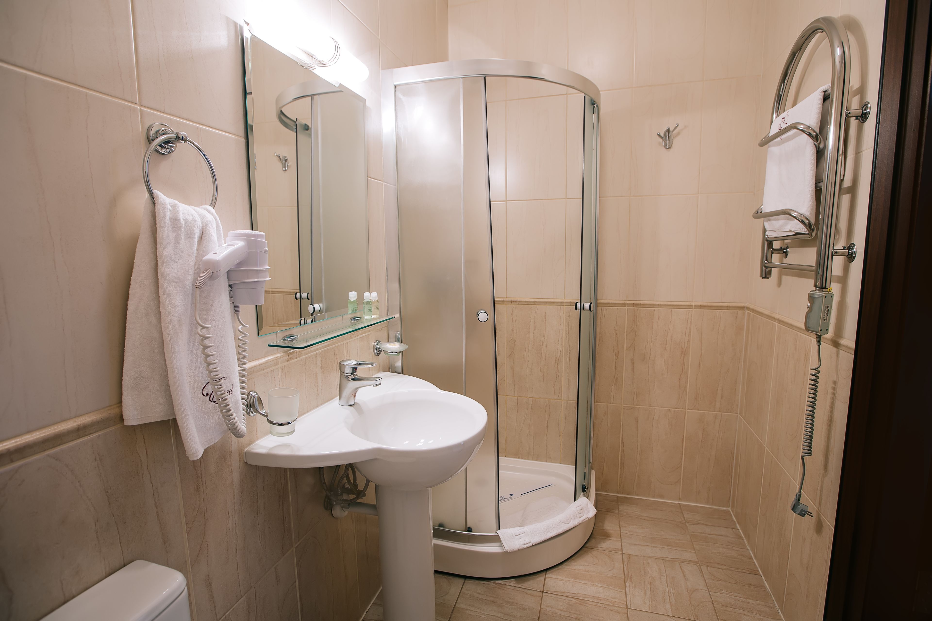 Un baño moderno con cabina de ducha de vidrio, un lavamanos con toallero y un inodoro.